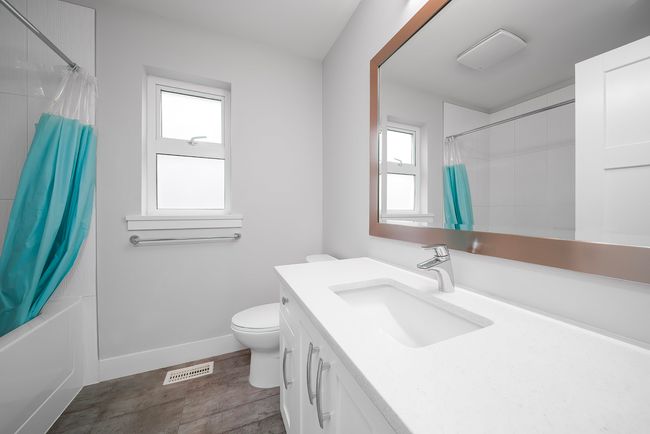 Bathroom with vanity, toilet, wood finished floors, shower / bath combo, and baseboards | Image 20