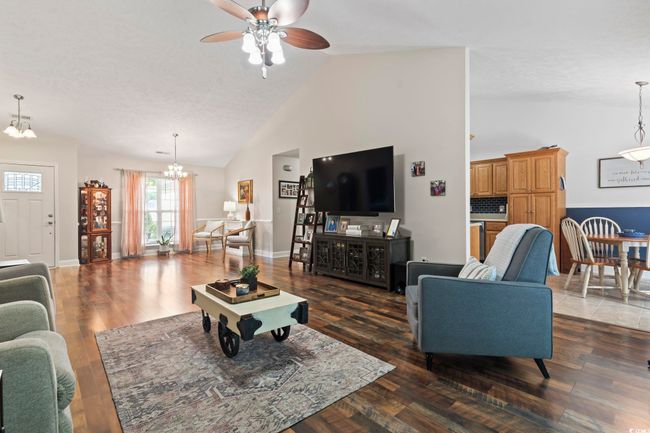 Living room featuring a chandelier, a ceiling fan, high vaulted ceiling, and wood finished floors | Image 5