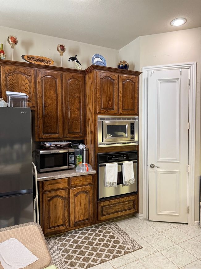 Kitchen featuring oven, fridge, light tile patterned floors, recessed lighting, and light countertops | Image 9