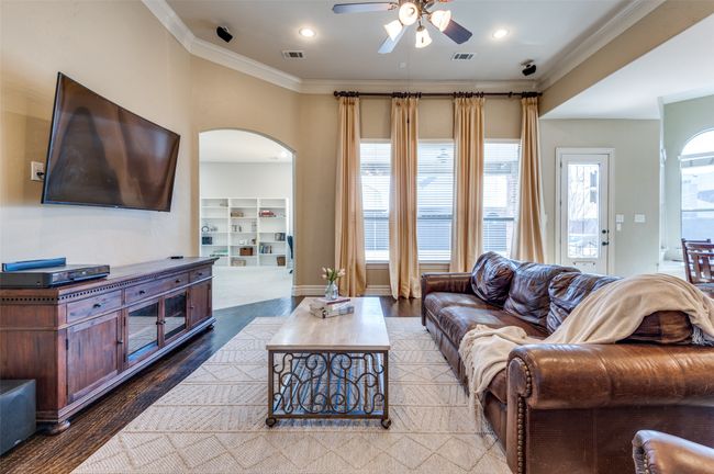 Living room featuring arched walkways, visible vents, a ceiling fan, and ornamental molding | Image 10