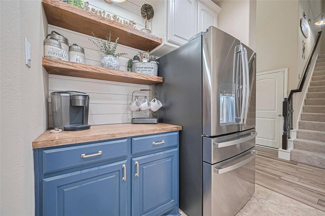 This stylish dry bar showcases custom cabinetry, shelving, and a shiplap wall, highlighted by a modern gold light fixture—an ideal nook for your morning coffee, just steps from the pantry. | Image 13