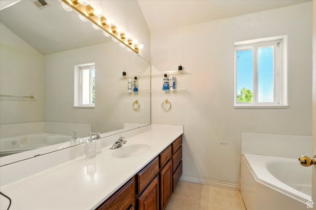 Full bathroom featuring vanity, a bath, baseboards, lofted ceiling, and tile patterned floors | Image 29