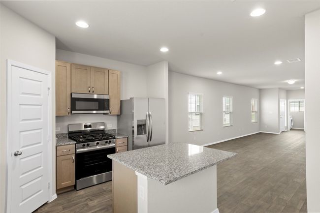 Kitchen featuring stainless steel appliances, recessed lighting, dark wood finished floors, light stone countertops, and a kitchen island | Image 19