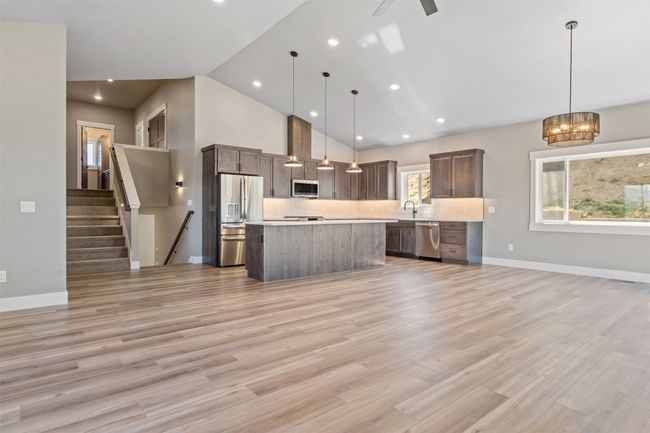 Kitchen with appliances with stainless steel finishes, open floor plan, light countertops, a kitchen island, and dark brown cabinetry | Image 11