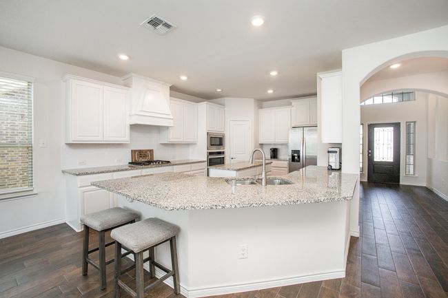 Kitchen with visible vents, dark wood-style flooring, a sink, stainless steel appliances, and custom range hood | Image 12