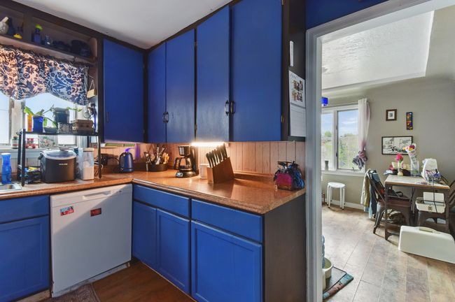 Kitchen with white dishwasher, blue cabinets, and wood finished floors | Image 17