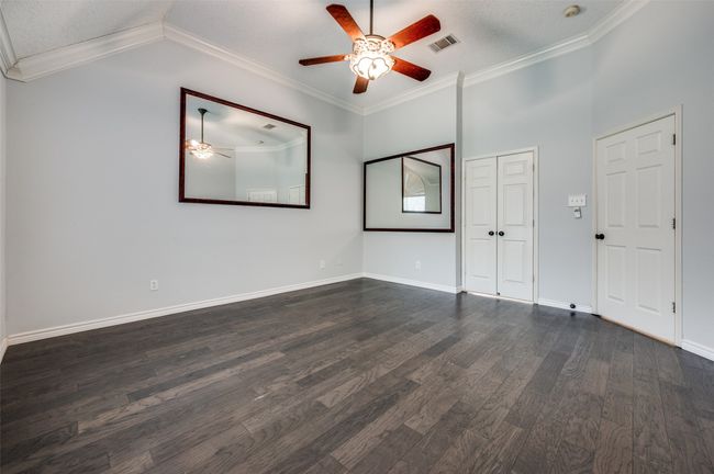 Spare room with dark wood-style floors, vaulted ceiling, visible vents, baseboards, and ceiling fan | Image 17