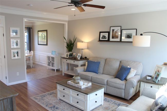 Living room featuring crown molding, ceiling fan, a wainscoted wall, wood finished floors, and a decorative wall | Image 8