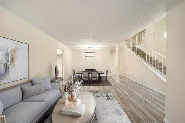 This photo has been virtually staged.The open-concept formal dining area seamlessly connects to the adjacent living space for versatile entertaining. Sleek neutral flooring, modern light fixture, and direct access to the staircase highlight the functional, welcoming layout at the heart of the home. This photo has been virtually staged. | Image 4