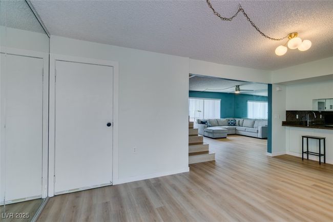 Living area with a textured ceiling, light wood-style flooring, and ceiling fan | Image 19