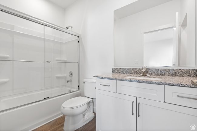 Full bathroom with toilet, vanity, wood finished floors, and bath / shower combo with glass door | Image 6