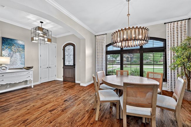 Dining space featuring a chandelier, wood finished floors, crown molding, and arched walkways | Image 4