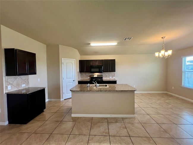 Kitchen featuring light tile patterned floors, black appliances, and backsplash | Image 23