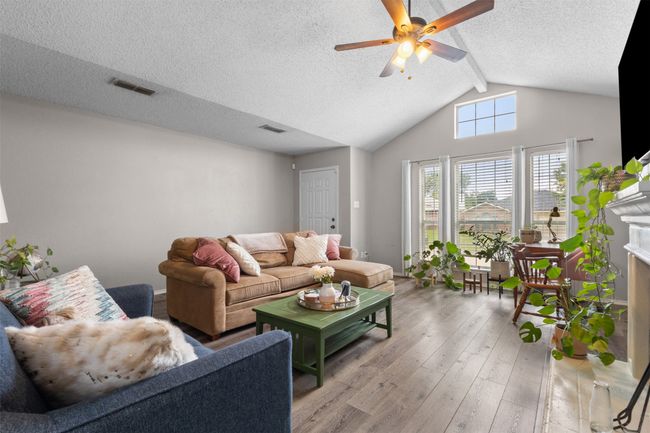 Living area featuring wood-type flooring, ceiling fan, a textured ceiling, and a fireplace | Image 11