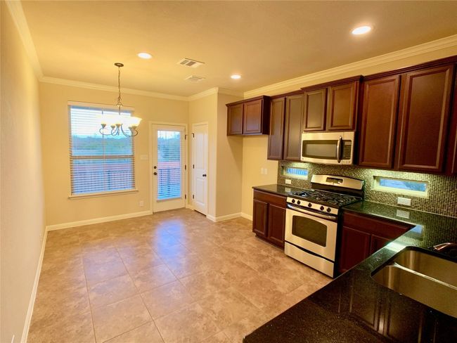 Kitchen featuring stainless steel appliances, a sink, a chandelier, tasteful backsplash, and ornamental molding | Image 15