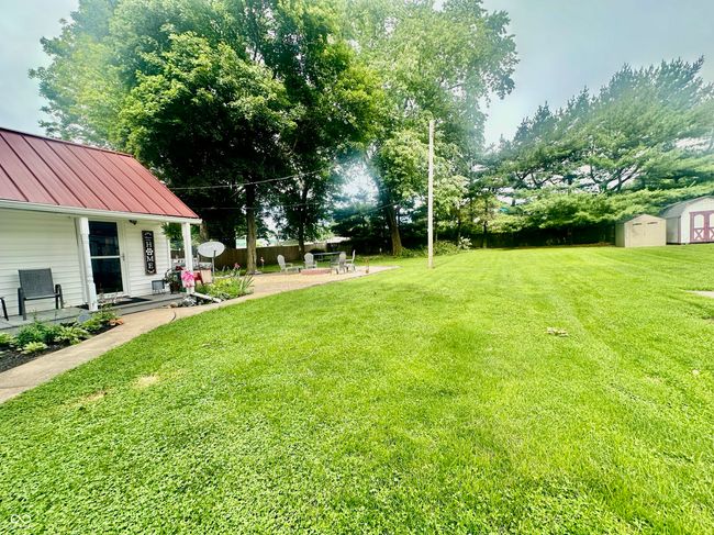 view of grassy yard with a storage unit and a patio area | Image 8