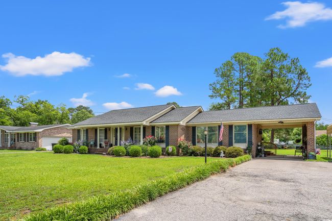 Single story home with driveway, a front yard, brick siding, an attached carport, and covered porch | Image 13