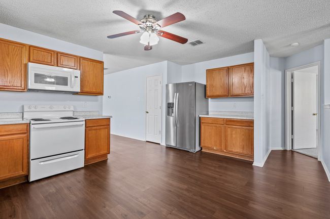 Kitchen featuring a textured ceiling, ceiling fan, dark hardwood / wood-style flooring, and white appliances | Image 7