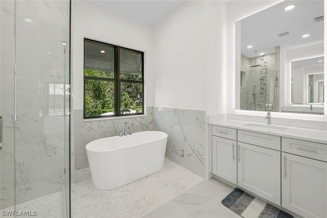 Master bath with freestanding soaking tub including handheld sprayer, His & Hers Quartz vanities with frameless backlit anti-fog mirrors with a 10' ceiling. | Image 10