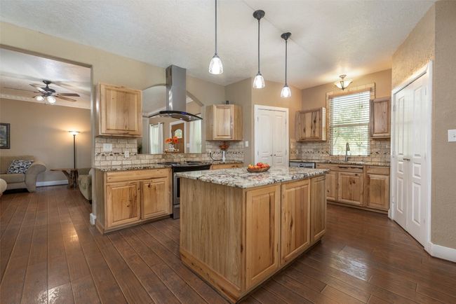 Kitchen featuring island exhaust hood, stainless steel appliances, a center island, and tasteful backsplash | Image 6