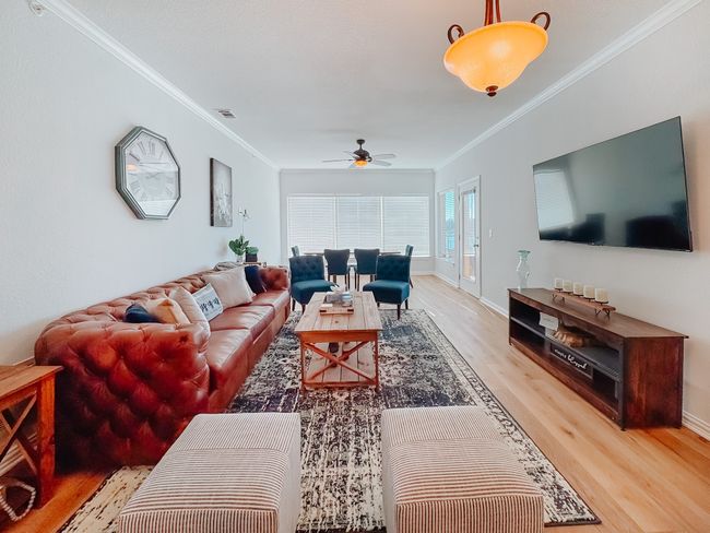 Living area featuring baseboards, ceiling fan, ornamental molding, and wood finished floors | Image 12