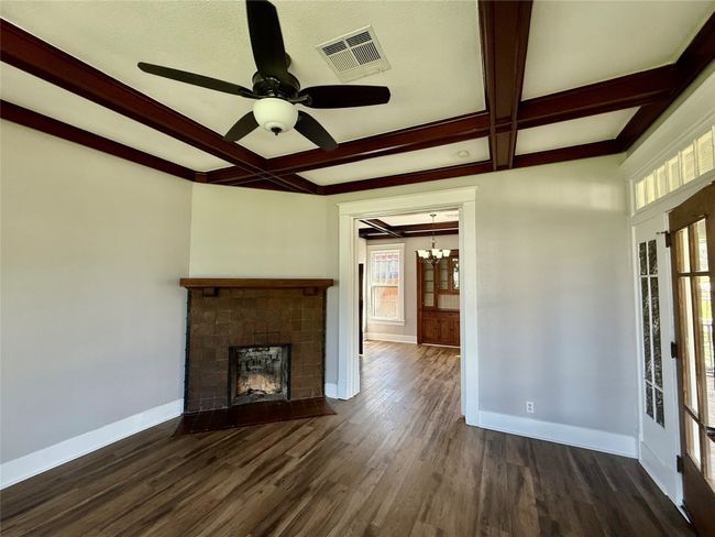 Unfurnished living room featuring coffered ceiling, a chandelier, a fireplace with flush hearth, dark wood-style floors, and beam ceiling | Image 7