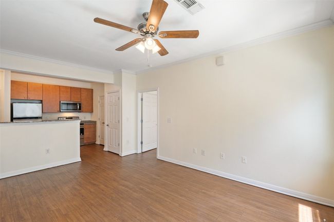 Unfurnished living room featuring crown molding, dark wood-type flooring, and ceiling fan | Image 10