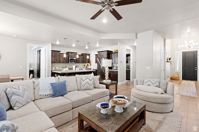 Living room with light wood-style floors, a ceiling fan, recessed lighting, and a chandelier | Image 51