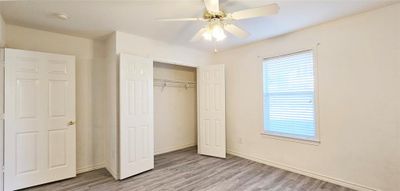 Unfurnished bedroom with light hardwood / wood-style flooring, a closet, and ceiling fan | Image 3