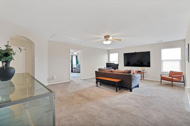 Living area with ceiling fan, light colored carpet, arched walkways, and attic access | Image 11