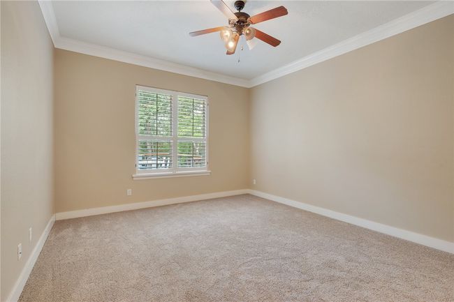 Carpeted spare room with crown molding, a ceiling fan, and baseboards | Image 18