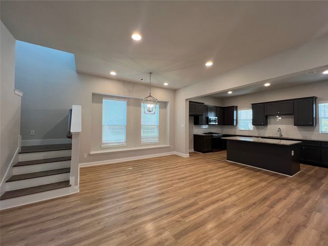 Kitchen with a sink, light wood finished floors, baseboards, recessed lighting, and a kitchen island | Image 5
