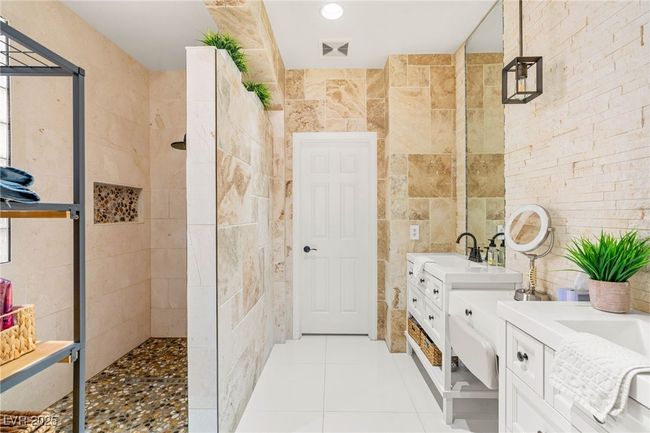 Bathroom with walk in shower, two vanities, tile walls, and tile patterned flooring | Image 17