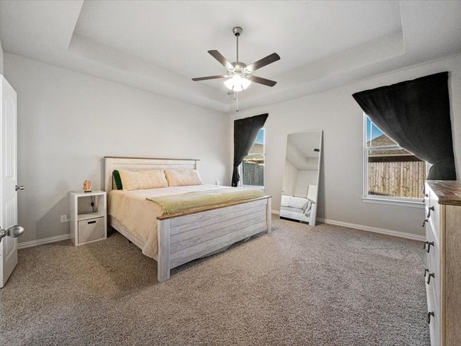 Carpeted bedroom featuring a ceiling fan, baseboards, and a tray ceiling | Image 14
