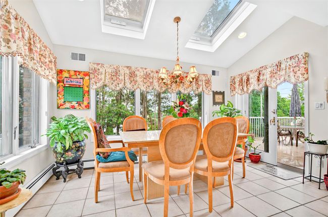 Dining space featuring a skylight, plenty of natural light, a chandelier, lofted ceiling, and light tile patterned floors | Image 23