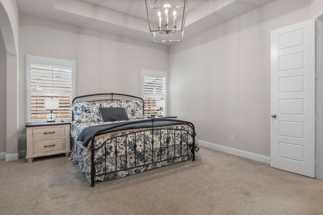 Carpeted bedroom featuring an inviting chandelier, baseboards, and a tray ceiling | Image 13