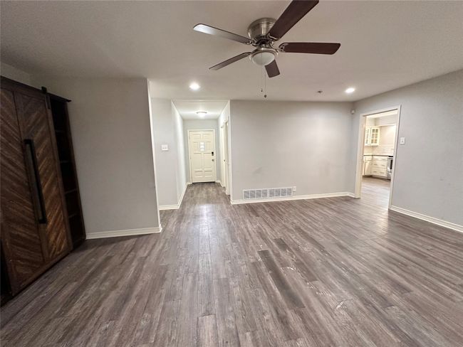 Spare room featuring dark wood-style floors, ceiling fan, recessed lighting, and a barn door | Image 7