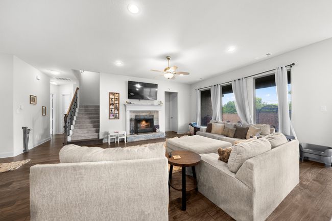 Living area with a stone fireplace, ceiling fan, dark wood-style floors, and recessed lighting | Image 4