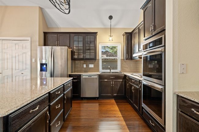 Kitchen with appliances with stainless steel finishes, backsplash, and dark brown cabinets | Image 12