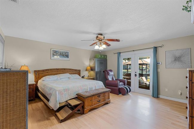 Primary bedroom with french doors to patio overlooking the water | Image 15