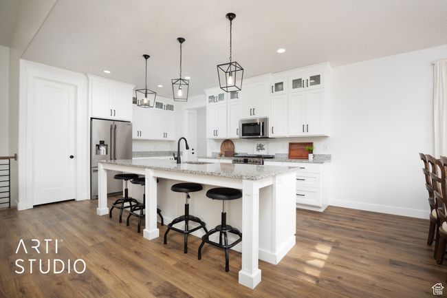 Kitchen with sink, a breakfast bar area, white cabinets, stainless steel appliances, and a center island with sink | Image 11