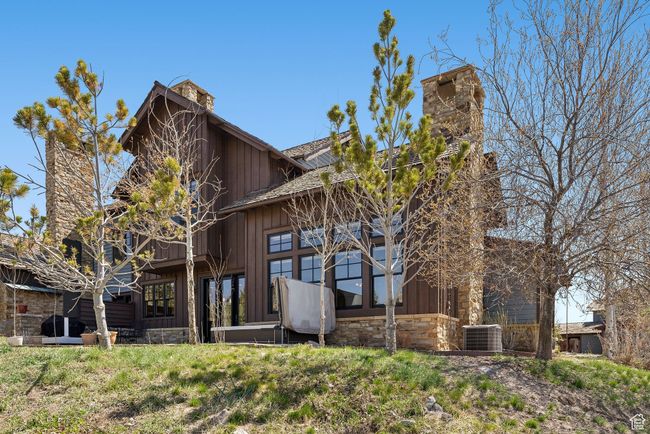 Back of house with board and batten siding, central AC unit, stone siding, and a chimney | Image 36