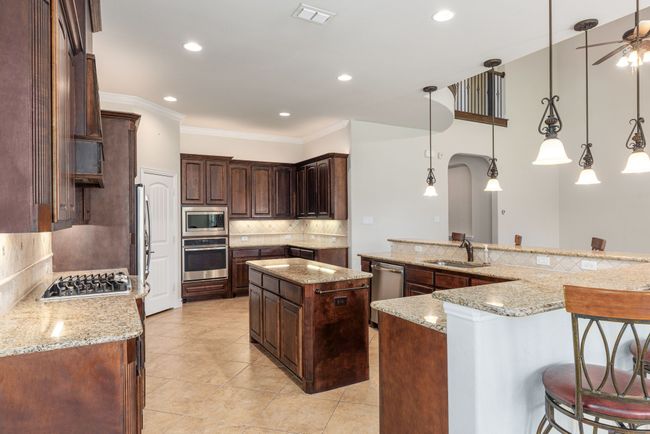 Kitchen featuring backsplash, visible vents, a sink, a kitchen island, and appliances with stainless steel finishes | Image 23