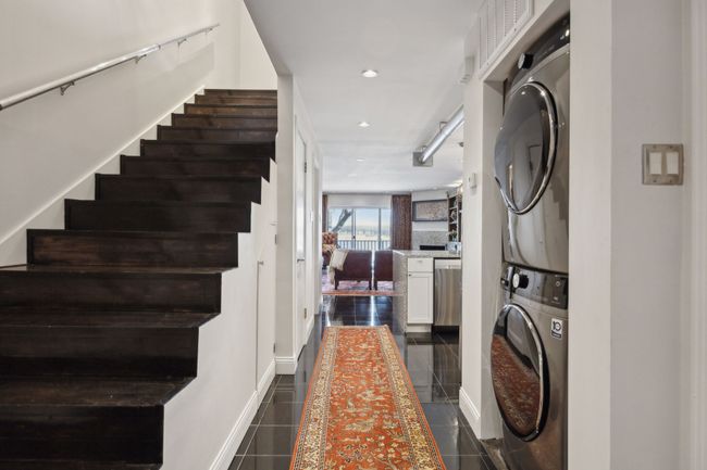 Entryway with lake views (with lots of space behind) and the stairway leading up to primary bedrooms and stackable washer and dryer, leads to kitchen and into living area. Half bath on the left side of hall. Storage under stairs, pantry and then half bath. | Image 8