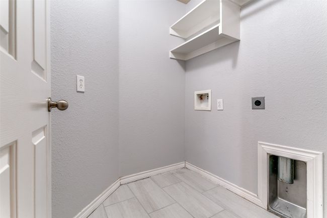 The dedicated laundry room has plenty of room to accommodate a full size washer and dryer, with a rack to hang your clothes and shelves to store all of your laundry products. | Image 30
