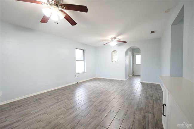 Spare room with ceiling fan, arched walkways, wood finished floors, and a smoke detector | Image 4