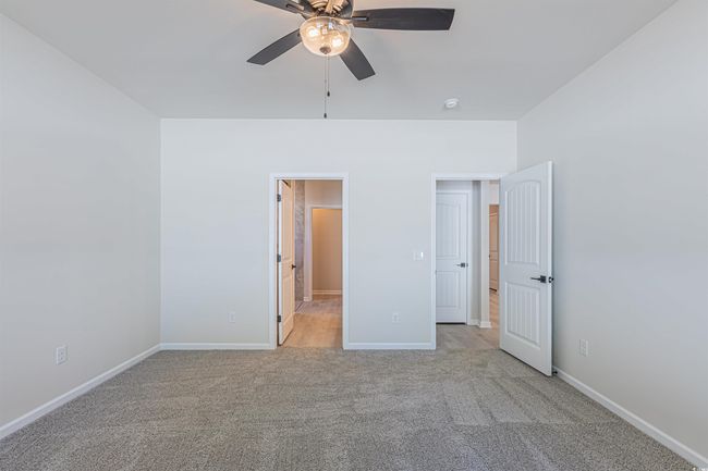 Unfurnished bedroom with a ceiling fan, light colored carpet, and baseboards | Image 13