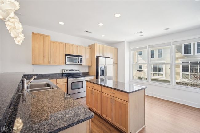 Kitchen with light brown cabinets, appliances with stainless steel finishes, wood finished floors, and a sink | Image 4