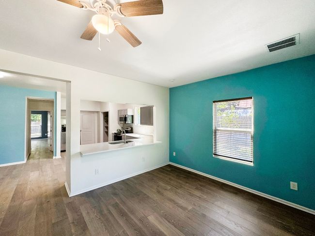 Unfurnished living room with dark wood finished floors, ceiling fan, baseboards, and a sink | Image 5