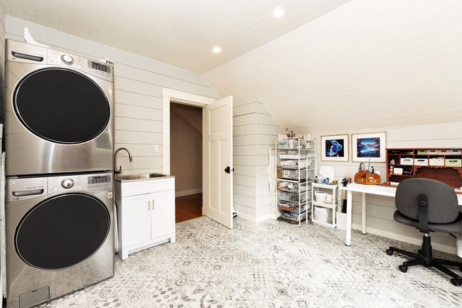 Washroom featuring wooden walls, recessed lighting, cabinet space, a sink, and stacked washer and clothes dryer | Image 19